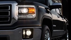2014 GMC Sierra projector-beam headlamps with chrome grille surround and chrome bumpers.