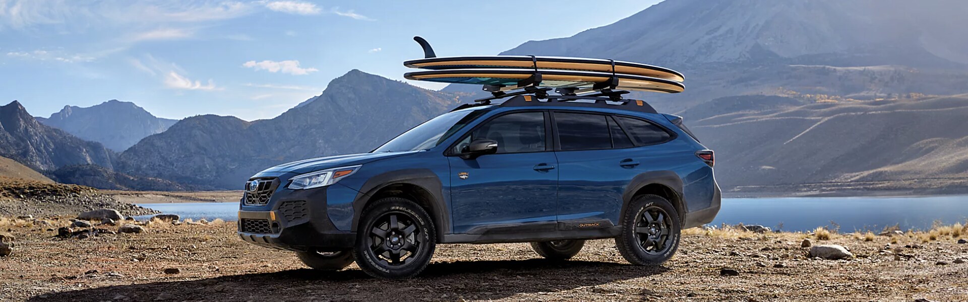 2024 Subaru Outback Wilderness parking next to a lake mountains in background.png 2024 Subaru Outback Wilderness parking next to a lake mountains in background