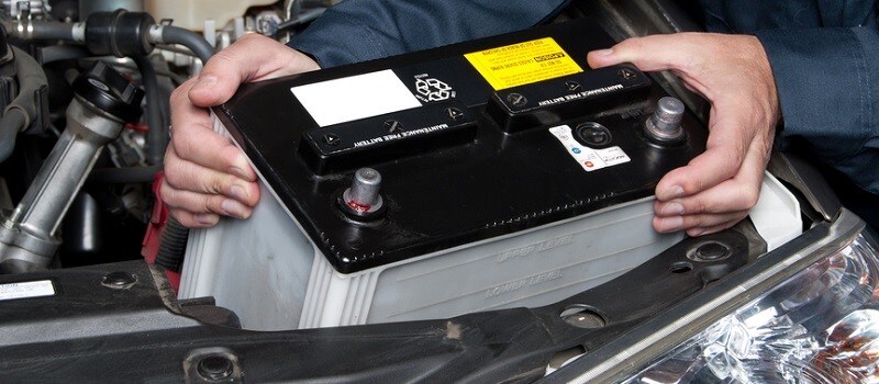 Auto mechanic replacing car battery