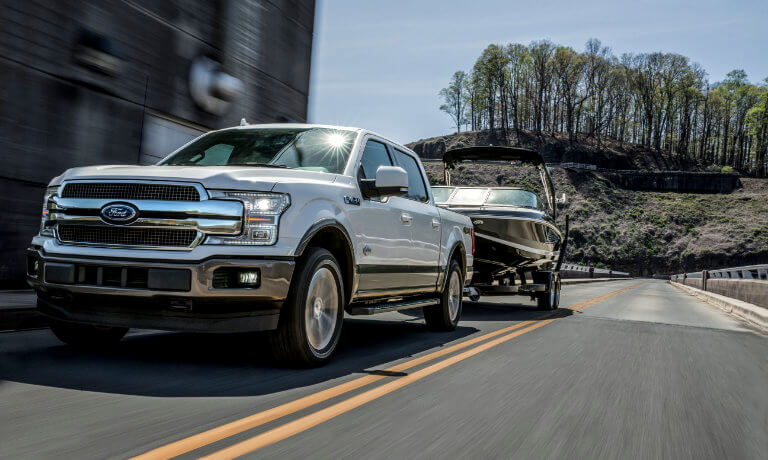 2019 Ford F-150 towing boat down street