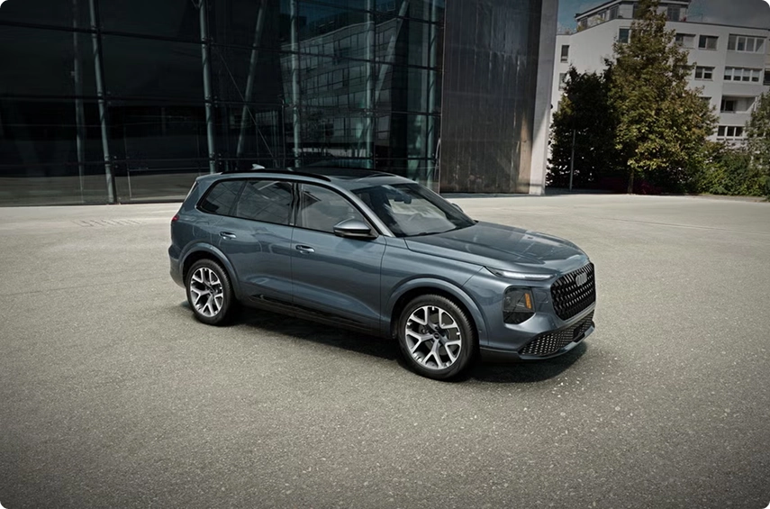 Gray Audi Q7 with the Black optic package parked in front of a glass building, front three-quarter view
