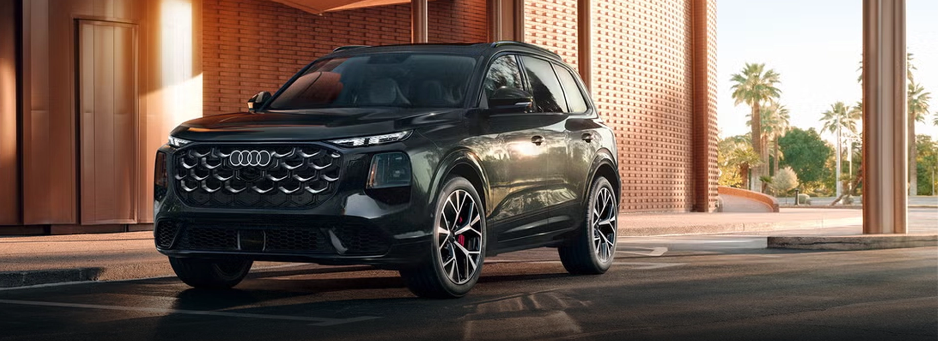 2027 Audi Q7 in dark green parked beneath a sunlit concrete building, front three-quarter view