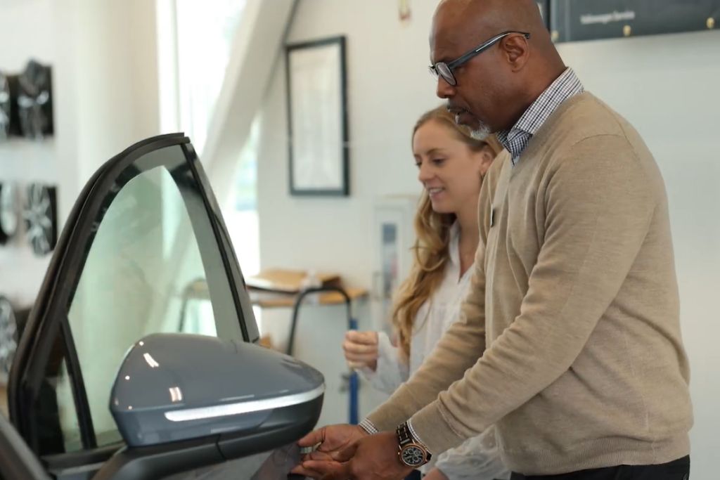 buy-vs-lease-audi-asheville.jpg Flow Automotive associate helping customer into car for a test drive