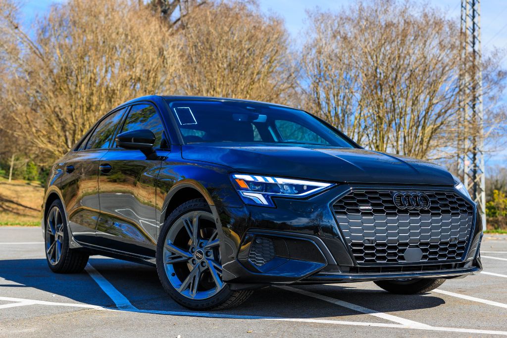 2024-audi-a3.jpg Black 2024 Audi A3 for sale, front view of sedan parked diagonally with trees and blue sky in background