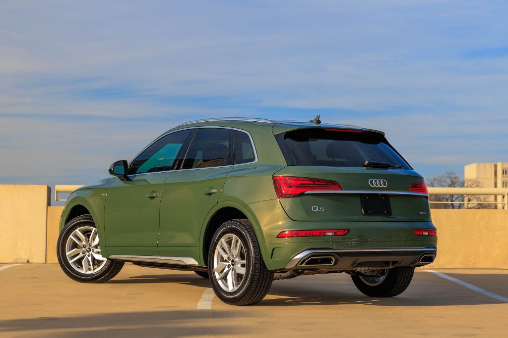 audi-q5-for-sale-nc.jpg 2024 Audi Q5 for sale shown in a district green exterior color, rear view of SUV parked diagonally with blue sky in background