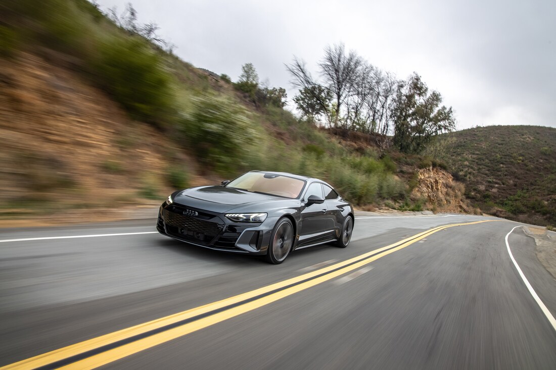 2022-Audi-etronGT-RS-Sedan-L12.png dark gray Audi e-tron GT sedan driving fast on a blurred highway curve