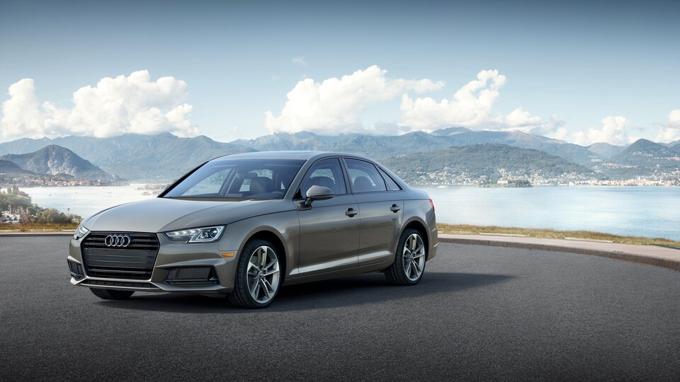 2019-Audi-A4-Titanium-Sedan-L01.png gray Audi A4 sedan parked on a lot overlooking a mountain lined beach