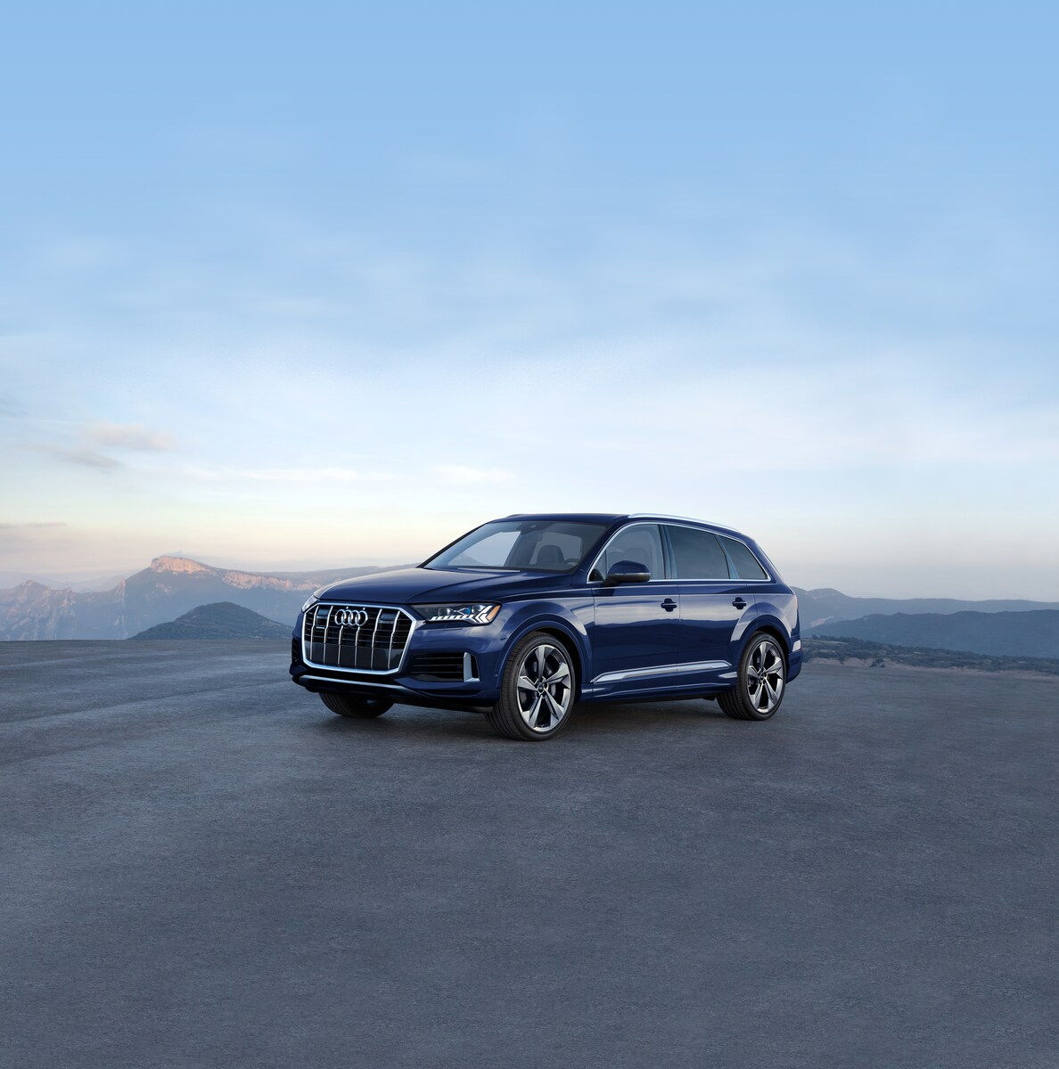 2023-Audi-Q7-Prestige-WheelAddOn-SUV-L05.png blue Audi Q7 SUV parked in an empty lot with a blue sky above