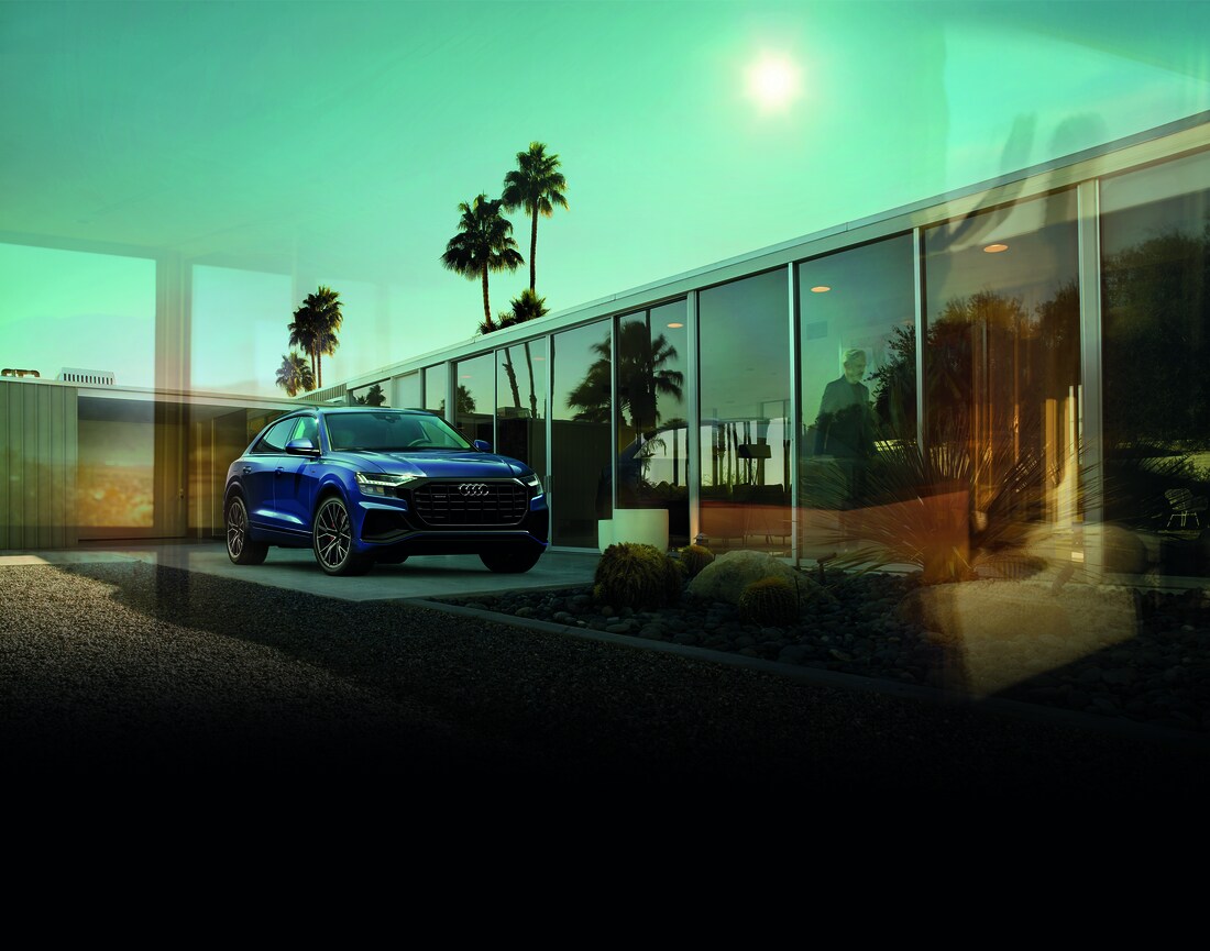 2022-Audi-Q8-PremiumPlus-BlackOpticsPackage-SUV-L02.png blue Audi Q8 SUV parked in front of a modern glass building