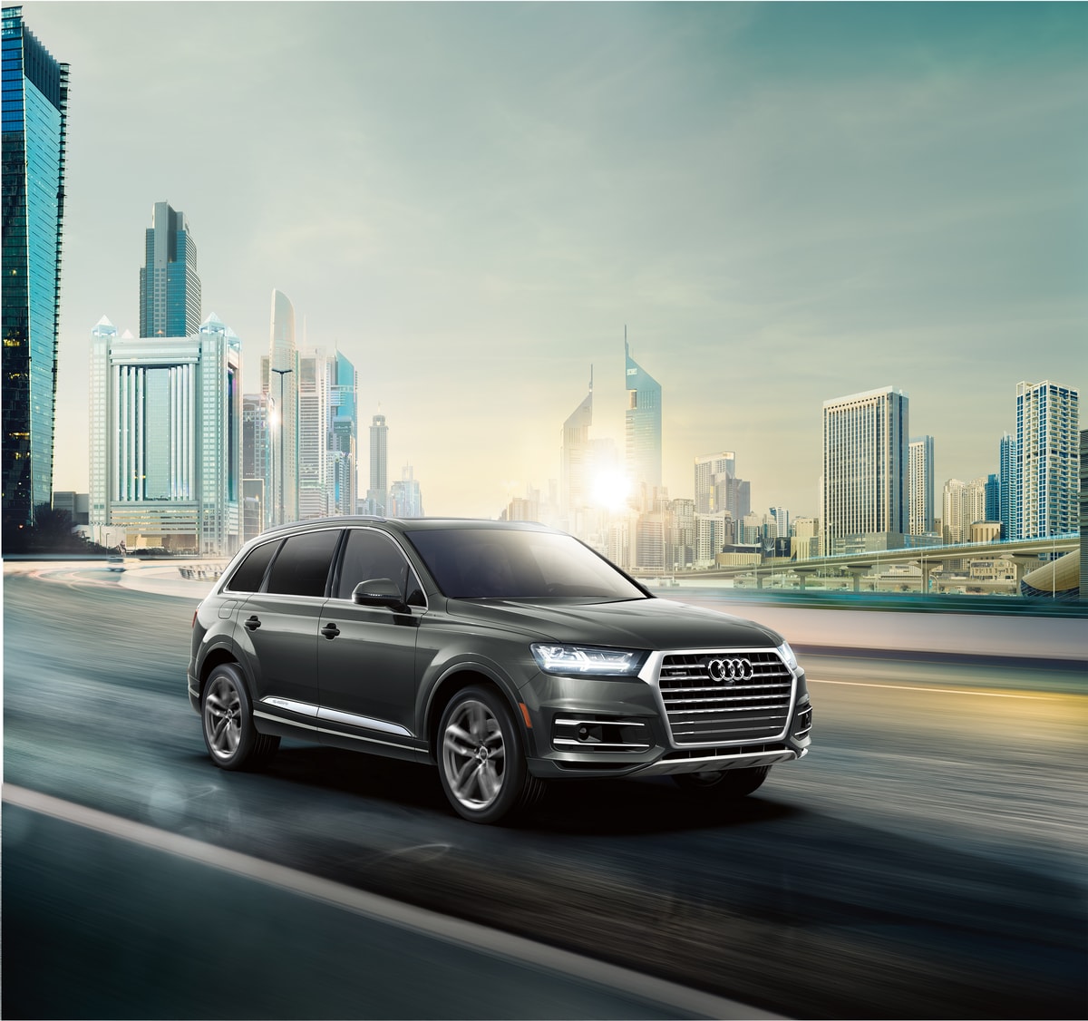 2018-Audi-Q7-Premium-SUV-L03.png black Audi Q7 SUV driving just outside of a cityscape