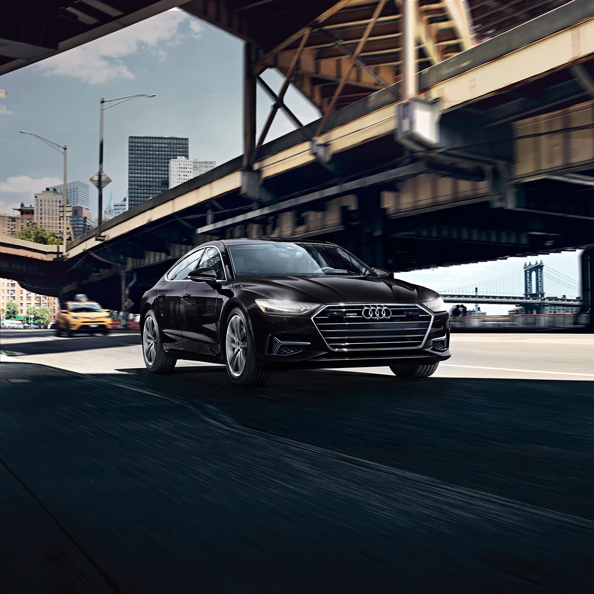 black Audi A7 luxury sedan driving through a city underpass