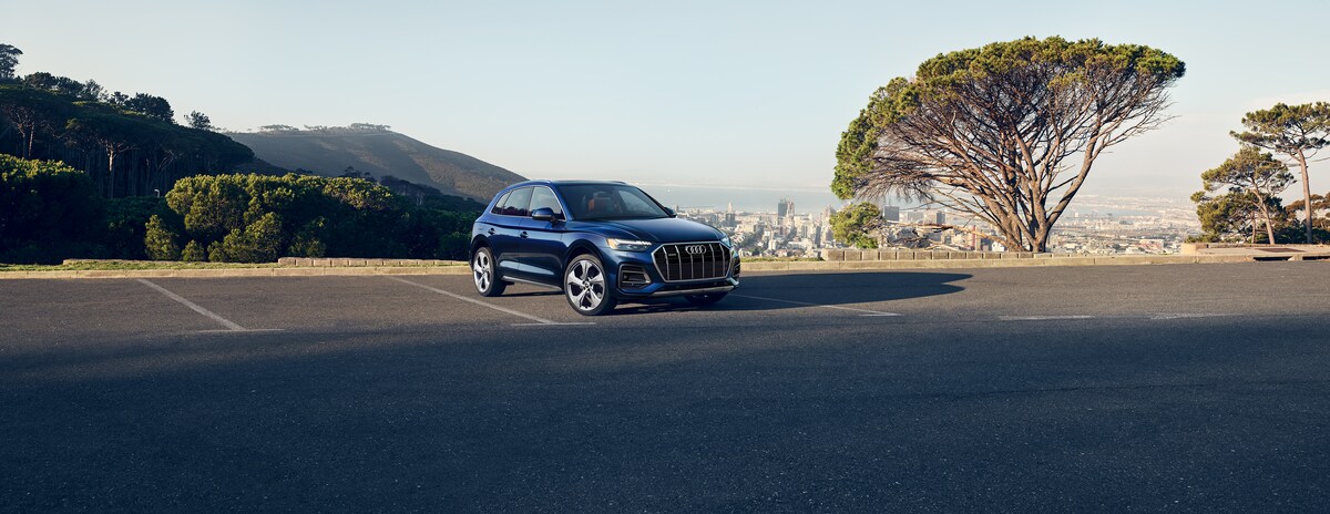 2021-Audi-Q5-PremiumPlus-45TFSI-WheelAddOn-SUV-L01.png blue Audi Q5 SUV parked in a large lot
