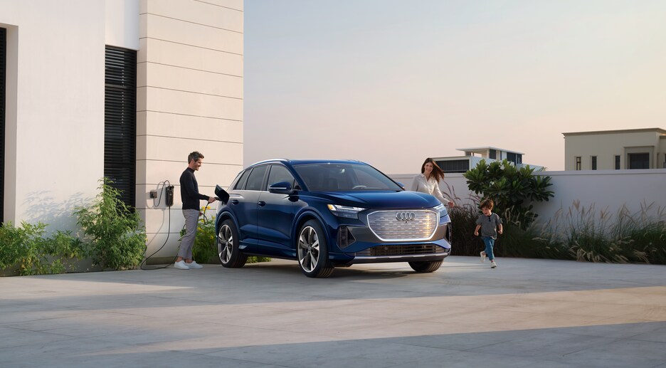 2022-Audi-Q4-Prestige-WheelAddOn-SUV.png blue Audi Q4 e-tron electric SUV parked in front of a modern apartment building