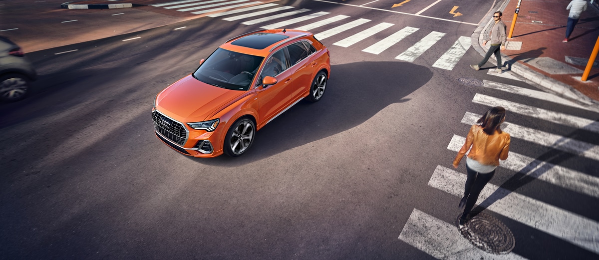 2021-Audi-Q3-Prestige-SUV-L01.png orange Audi Q3 SUV driving around a busy city corner, aerial view