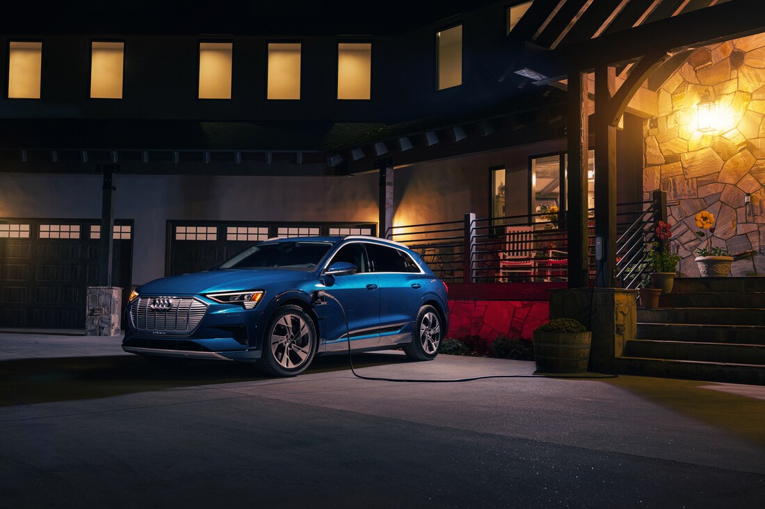 2023-Audi-etron-PremiumPlus-SUV-L01.png blue Audi e-tron SUV plugged into a home charging station