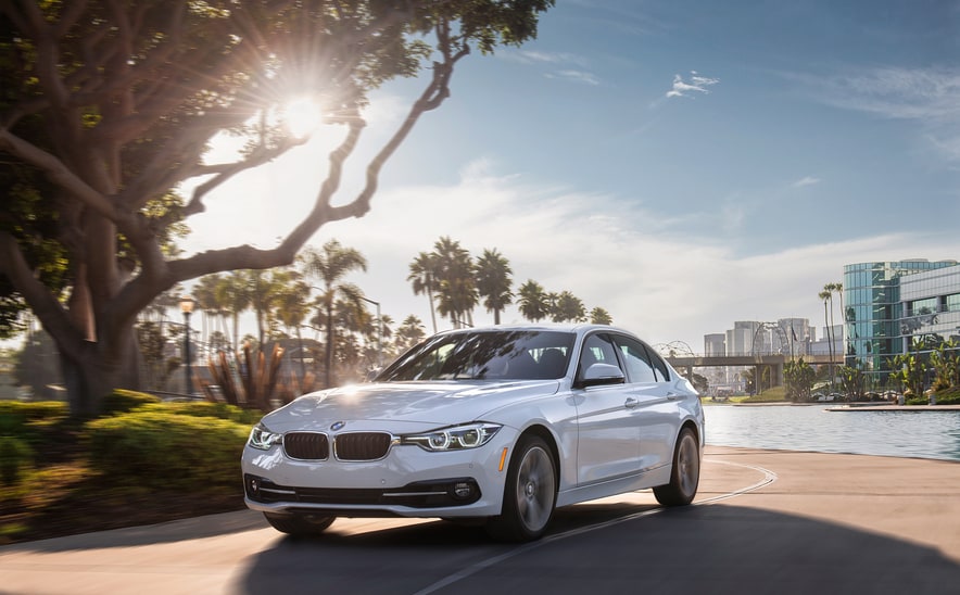 2018-BMW-3Series-330i-Sedan-L01.png white BMW 3Series 330i sedan parked underneath a tree on a sunny day