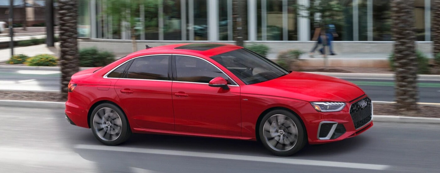 red-audi-driving-through-city-street