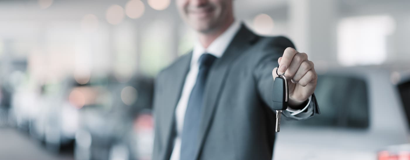 Luxury auto salesman handing over keys to car