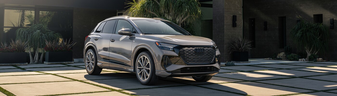Audi Q4 e-tron Gray Audi Q4 e-tron parked in front of a glass front home