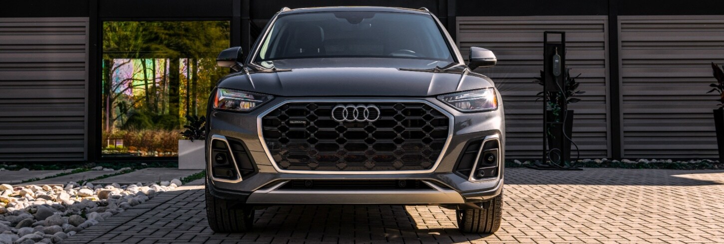 Audi Q5 e Grey Audi Q5 e charging by a beach house garage