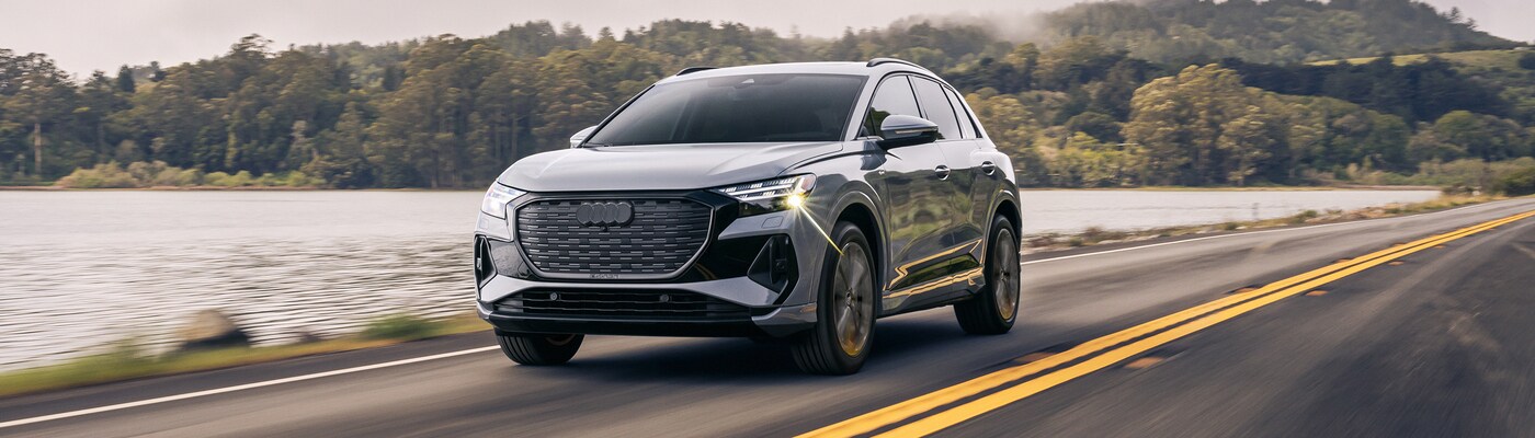 Audi Q4 e-tron Gray Audi Q4 e-tron in front of modern building with large windows