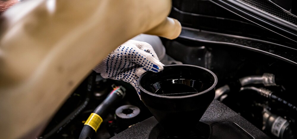 Benefits of Changing Your Audi’s Oil at Audi Owings Mills in Owings Mills | Service Advisor Putting New Oil in Vehicle