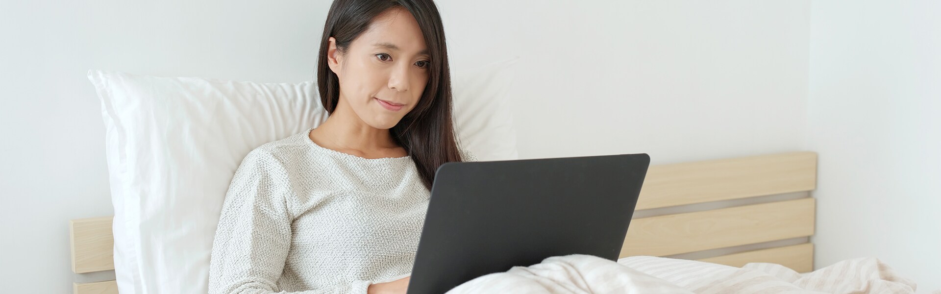 Shop from Home at Audi Owings Mills | Woman Using Her Laptop While Lounging in Bed