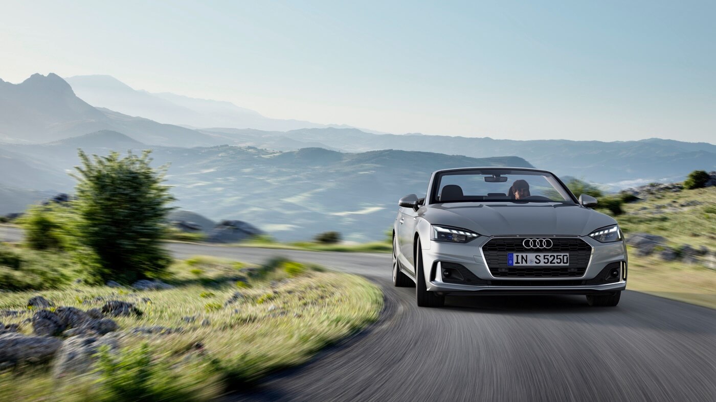 L'Audi A5 cabriolet Gris Chronos métallisé roulant sur une route.