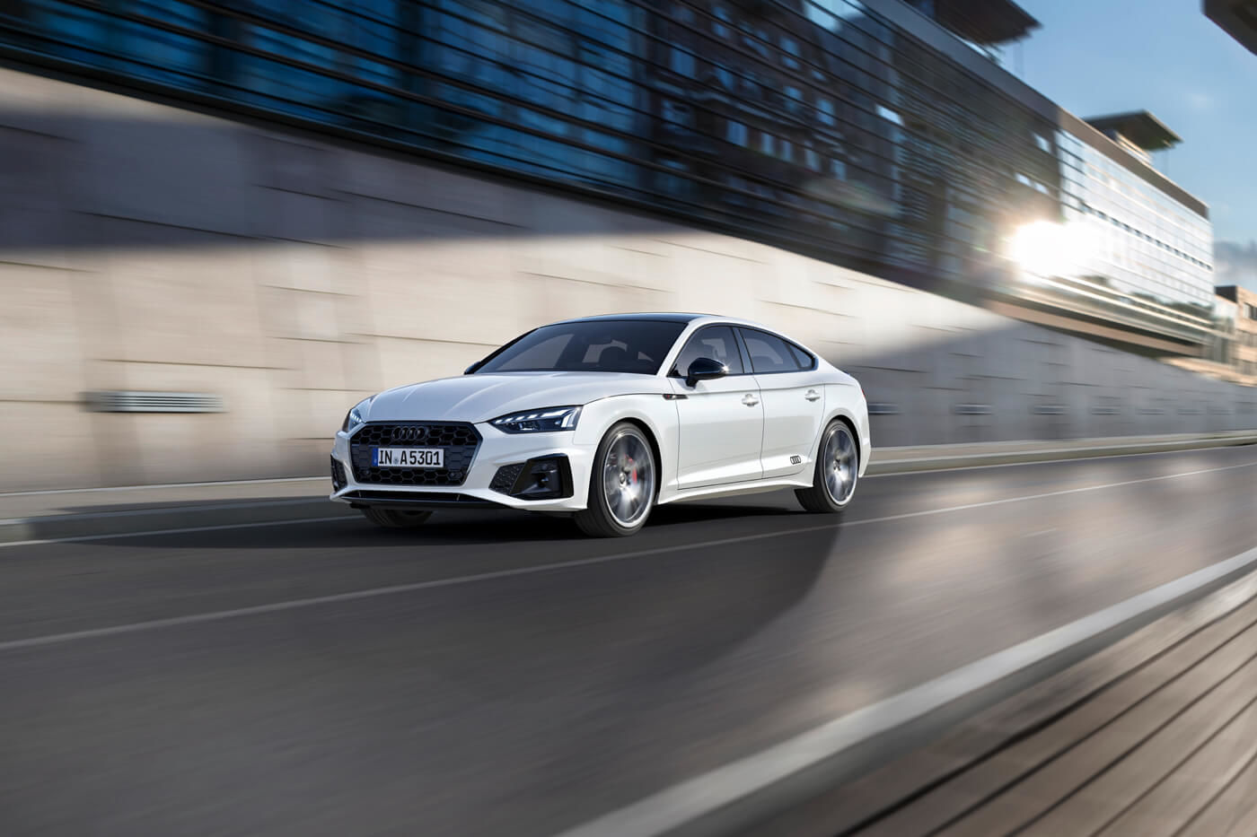 Vue 3/4 avant d'une berline Audi A5 Sportback couleur blanc Ibis roulant sur une route