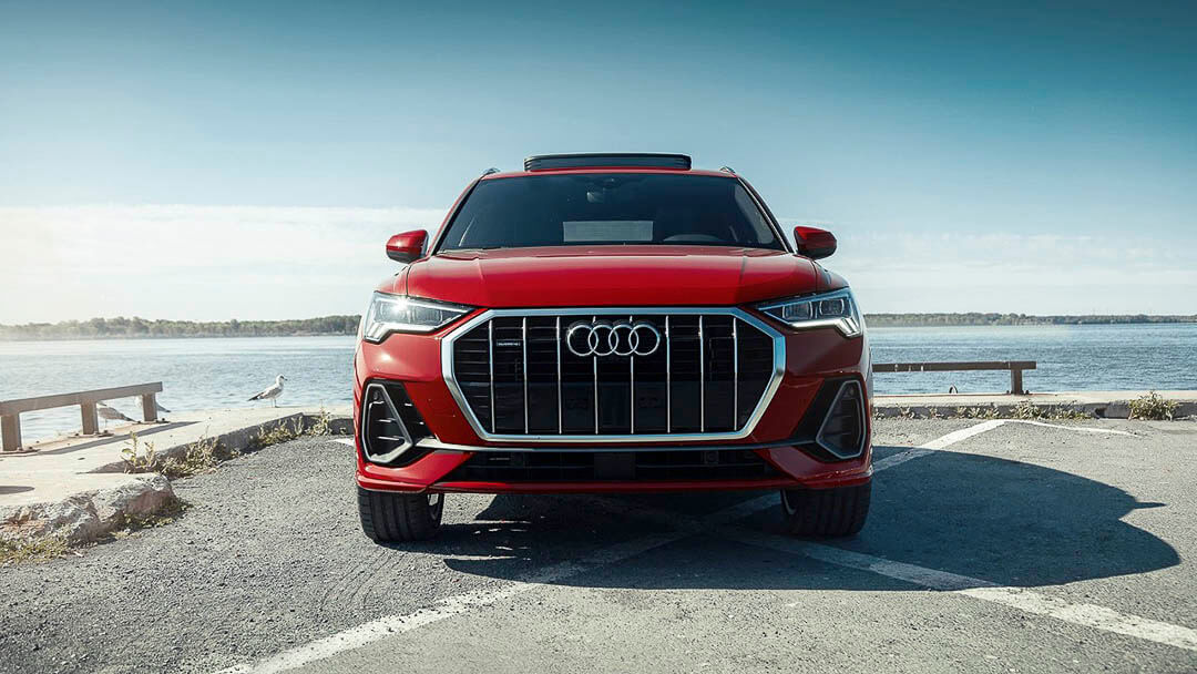 Vue avant d'un VUS Audi Q3 2021 rouge garé sur un quai au bord de la mer