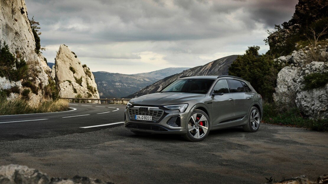 vue latérale avant d'une Audi Q8 e-tron 2023 sur le bord d'une route en montagne