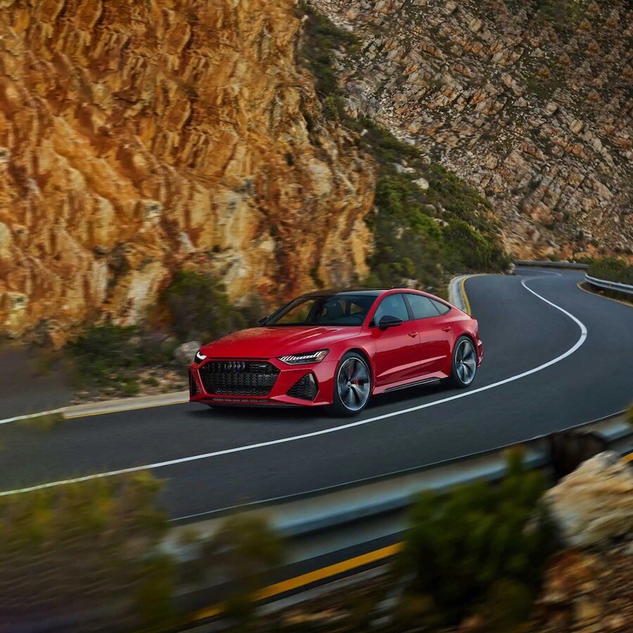L’Audi RS7 2023 rouge performant sur une route au bord d'une falaise.