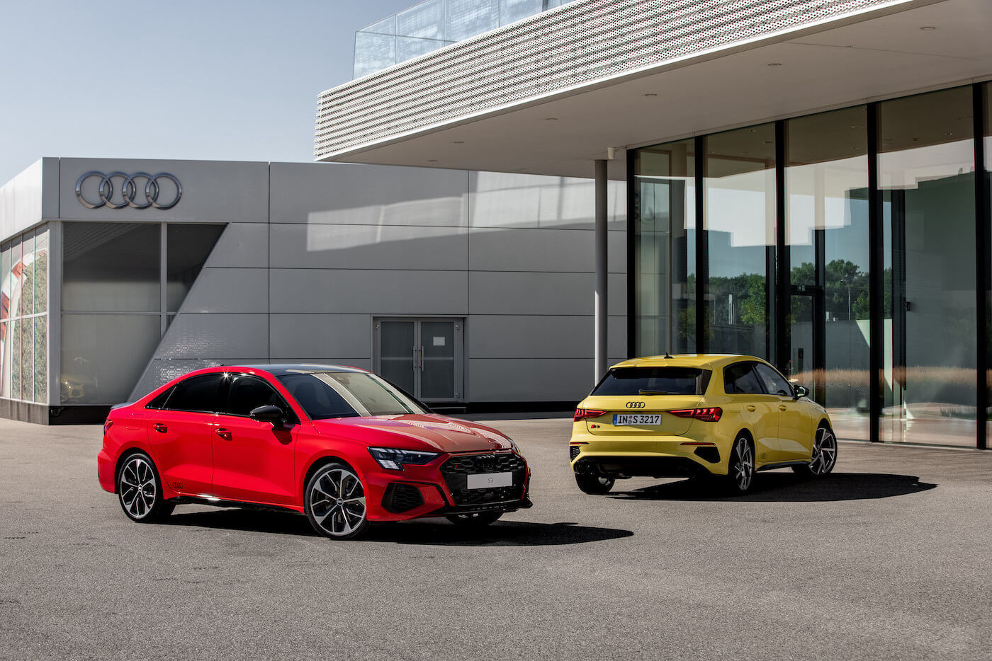 Une berline Audi A3 Rouge Tango et une version Sportback Jaune Python stationné chez un concessionnaire Audi