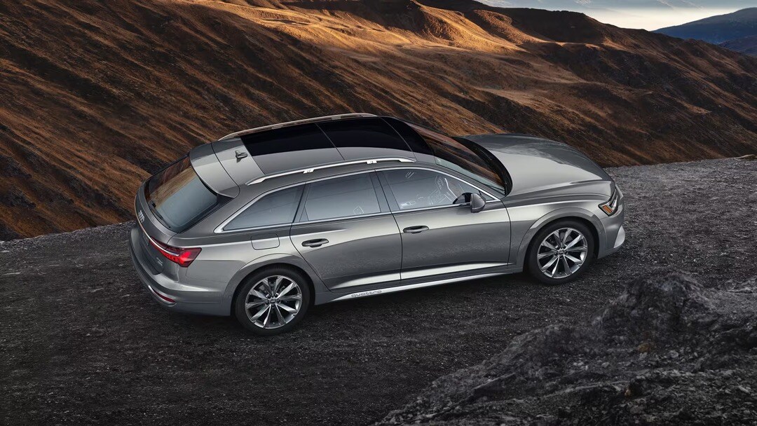Vue latérale et de dessus de l'Audi A6 allroad 2023 garé sur un chemin en montagne.