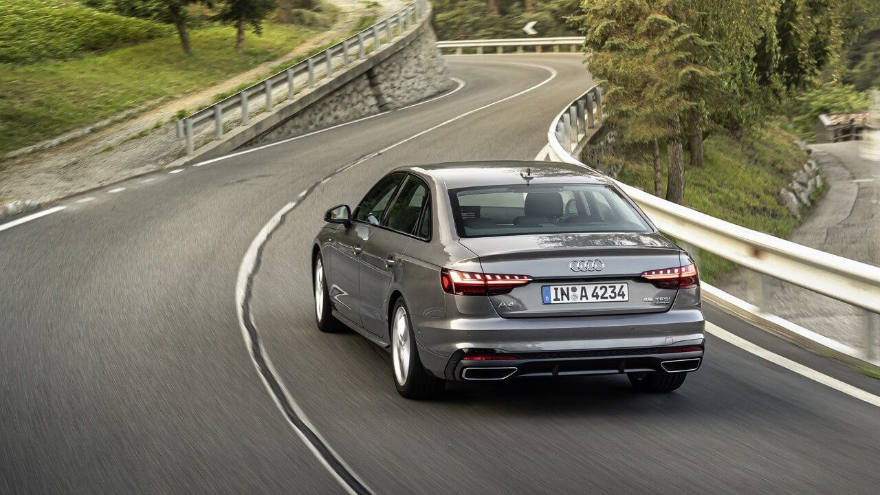 Vue 3/4 arrière d'une berline Audi A4 grise roulant sur une route