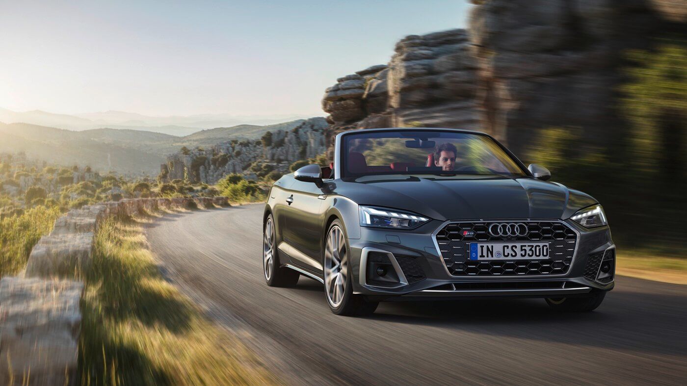 Vue 3/4 avant d'un Audi S5 Sportback TFSI gris roulant sur une route