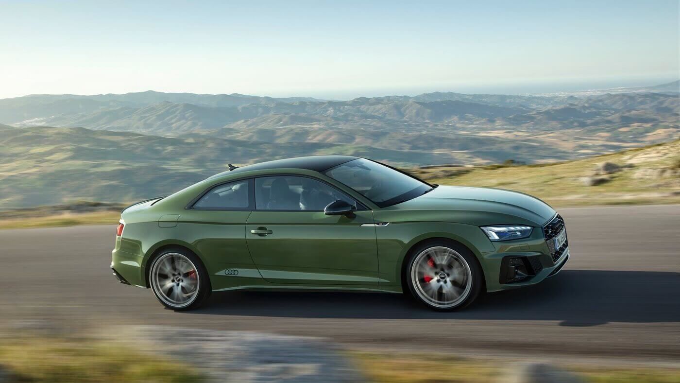 Un Audi A5 coupé 2022 Vert District roulant sur une route avec des montagnes visibles au loin