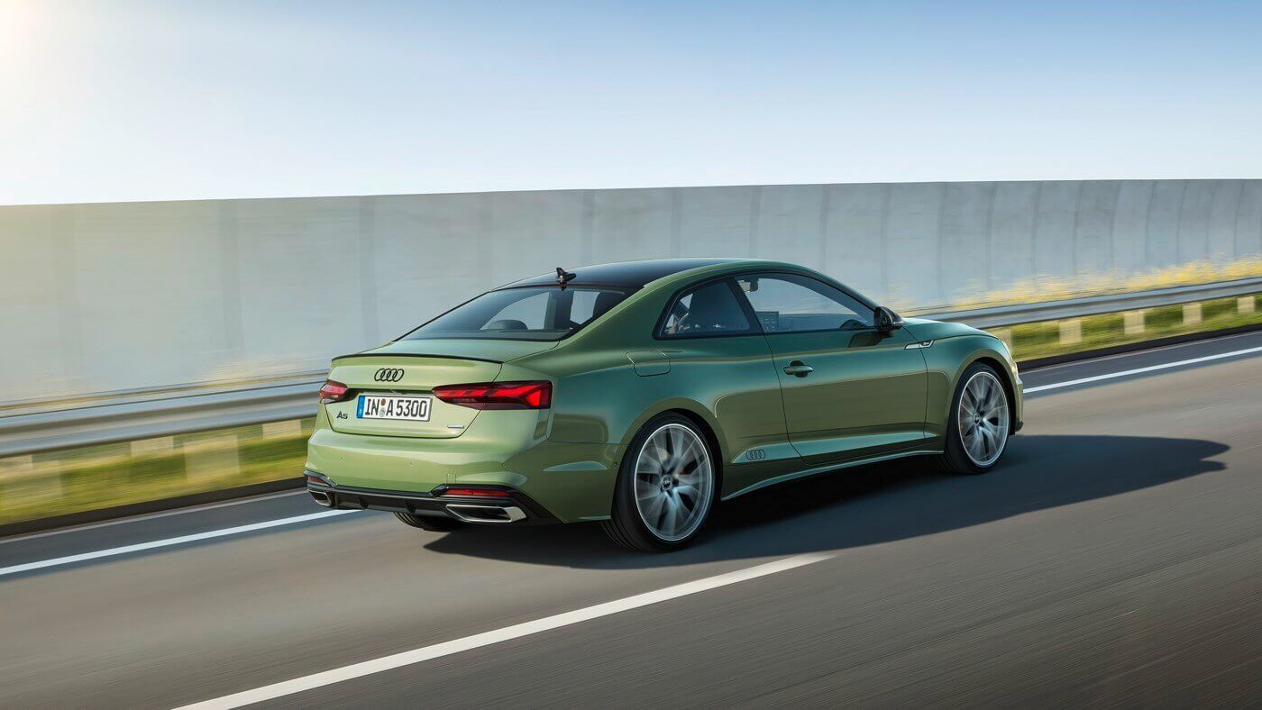 Vue latérale 3/4 arrière d'une berline Audi A5 Coupé 2022 Vert District roulant sur une route