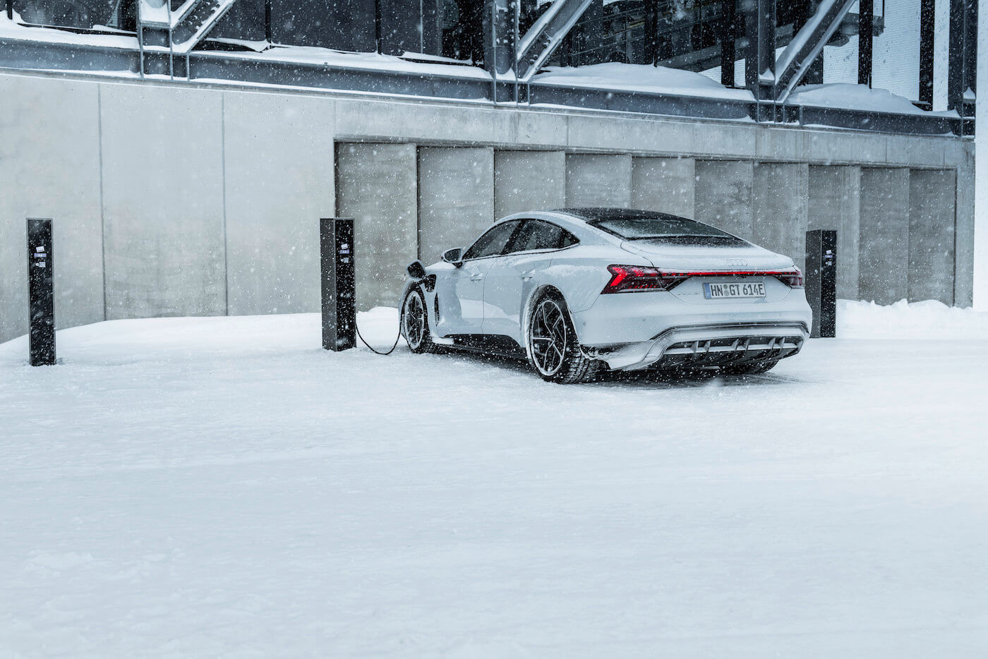Vue 3/4 arrière d'un Audi e-tron GT quattro Gris Suzuka en recharge sur une borne électrique en hiver