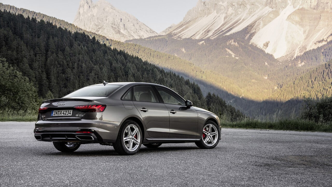 Vue 3/4 arrière d'une berline Audi A4 grise face à des montagnes