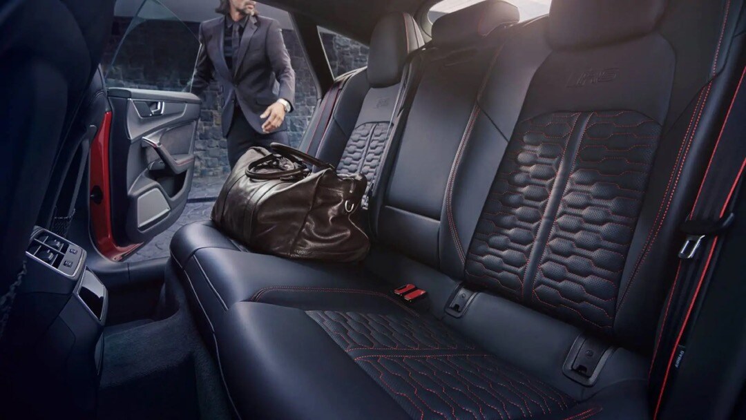 Homme ramassant sa valise sur la banquette de l'Audi RS7 2023.