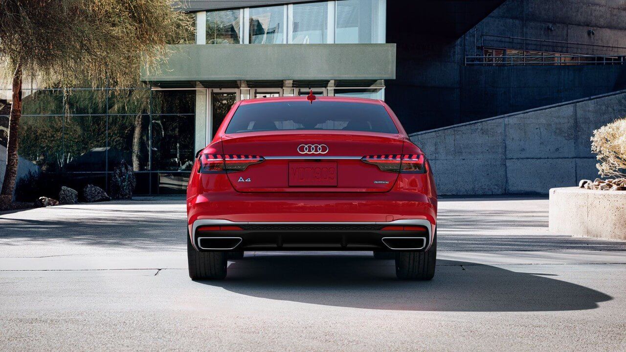 Vue arrière d'une berline Audi A4 rouge garée dans un stationnement d'un édifice