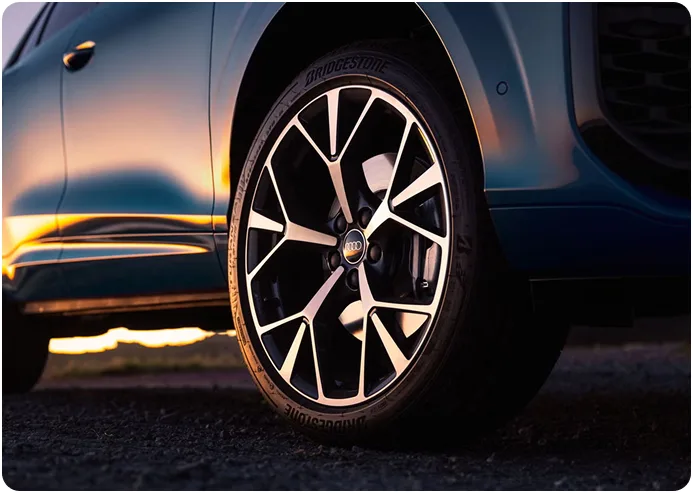 Close-up of the Audi Q3 alloy wheel and front fender at sunset
