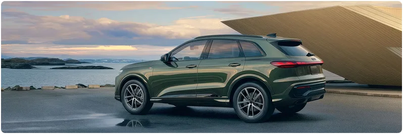 Green Audi Q5 parked beside the water at dusk, seen in profile