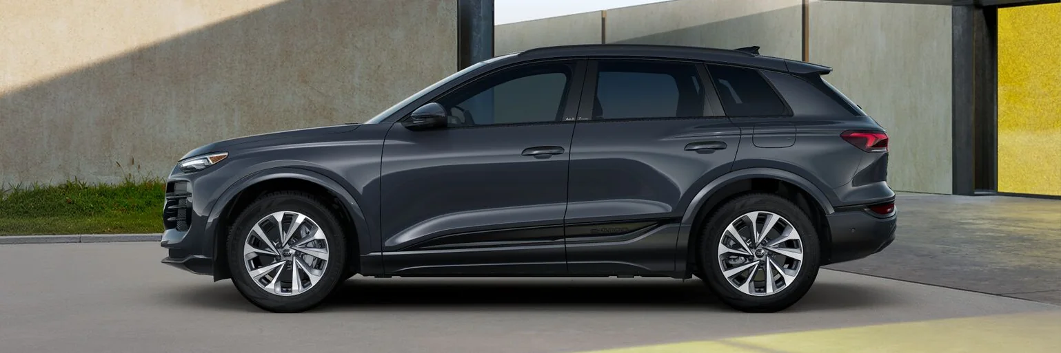 Grey Audi Q6 e-tron in profile in front of a yellow wall