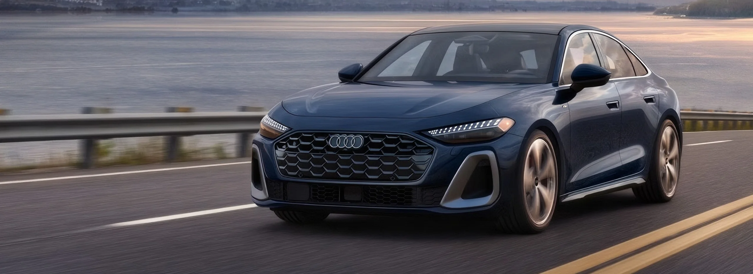 Blue 2027 Audi A5 sedan driving along a waterfront highway at sunset