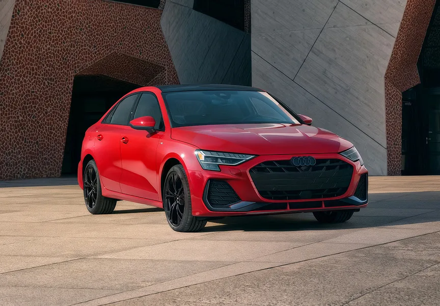 Red Audi A3 parked in front of a concrete structure, seen from the front three-quarter angle