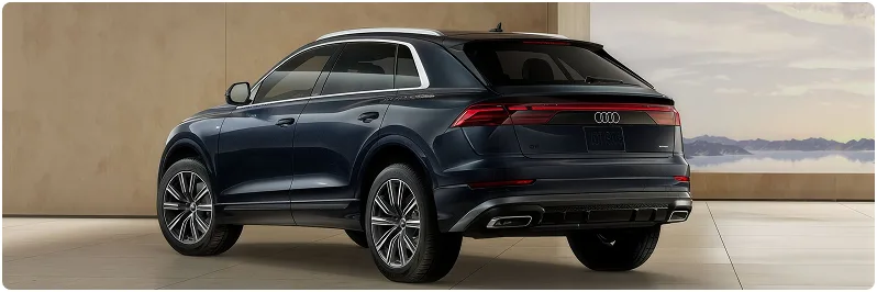 Blue Audi Q8 seen from the rear three-quarter angle in a stone-walled studio