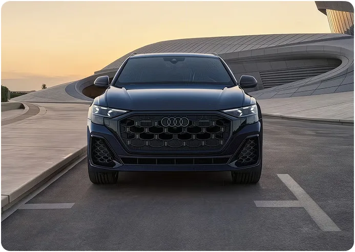 Blue Audi Q8 at dusk with its HD Matrix-design LED headlights lit, seen head-on