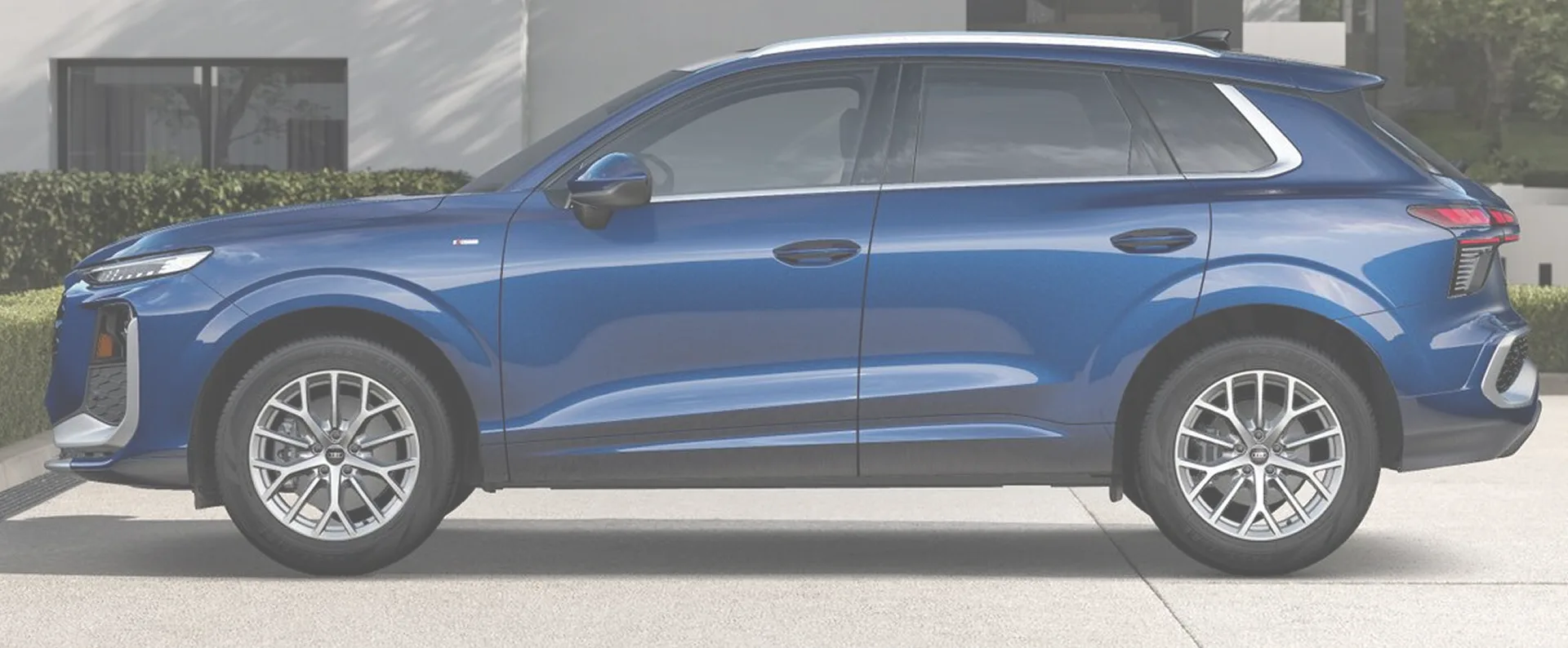 Blue Audi Q3 parked in profile outside a modern building, used as a washed-out backdrop